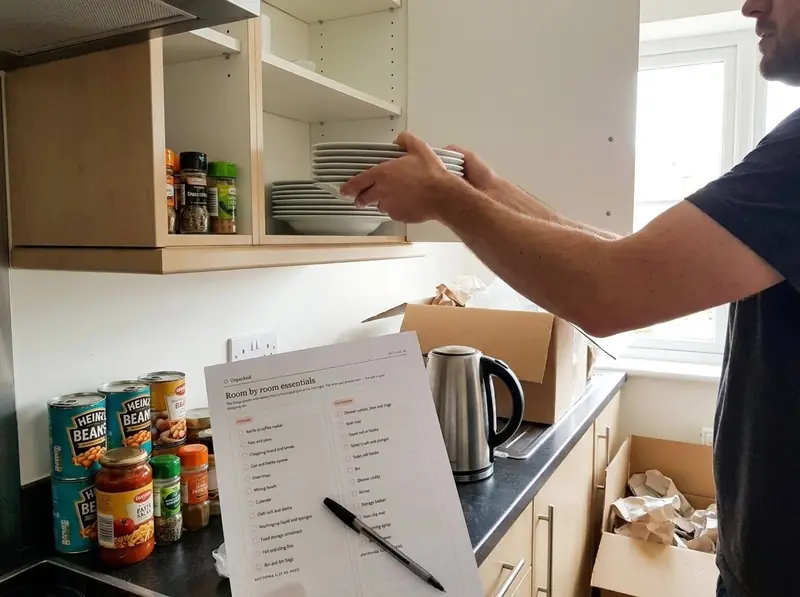 A customer unpacking kitchen items while using the Unpacked room-by-room essentials checklist.